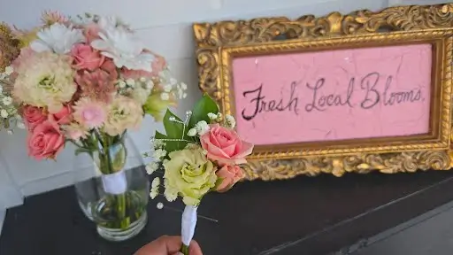 Pastel vase arrangement beside a Fresh. Local. Blooms. sign