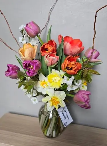 Spring vase arrangement of tulips, daffodils and curly willow