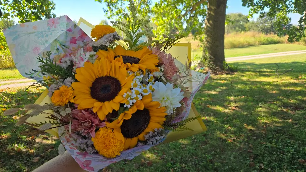 Hand-wrapped bouquet of sunflowers and garden blooms